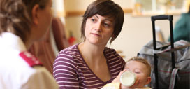 Young mum holding a baby and talking to Salvation Army officer