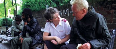 Salvationist sitting and talking with men on the street
